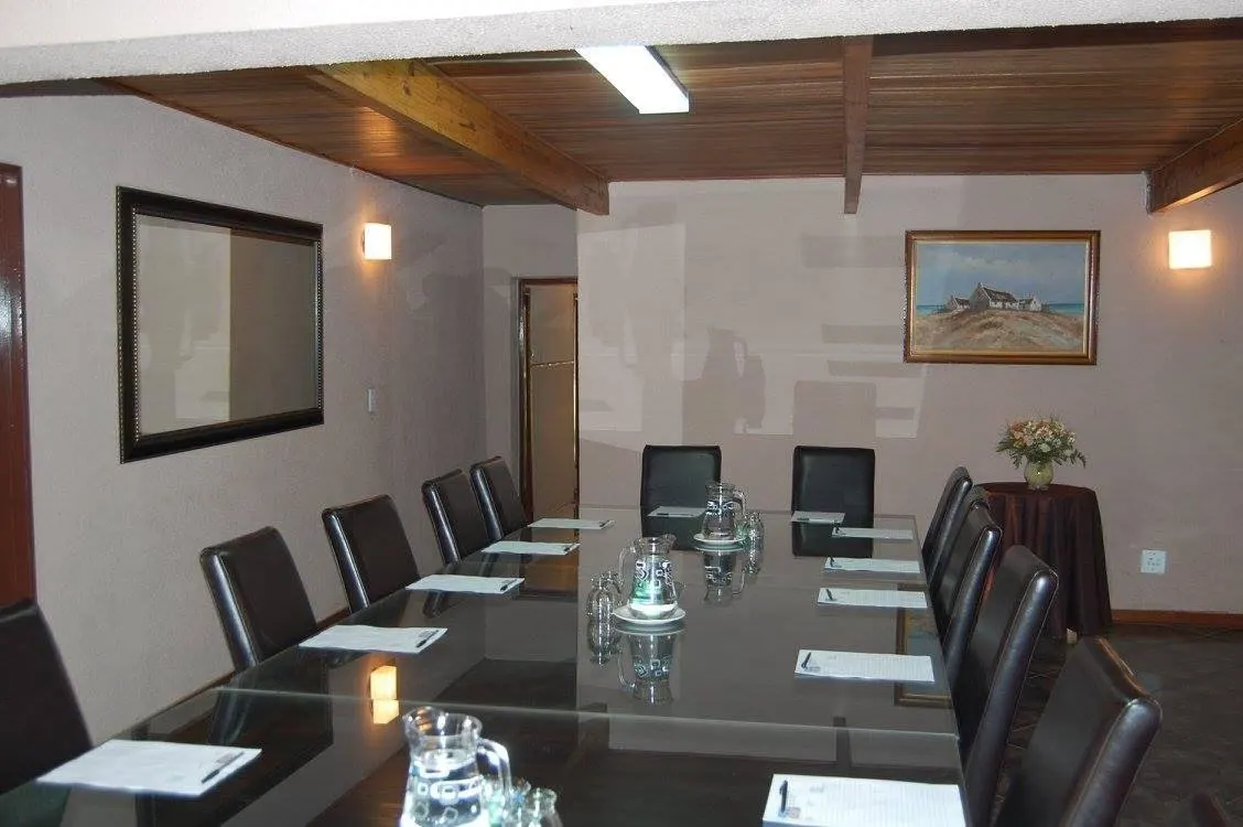 A boardroom set up with a long table, chairs and a wall-mounted screen