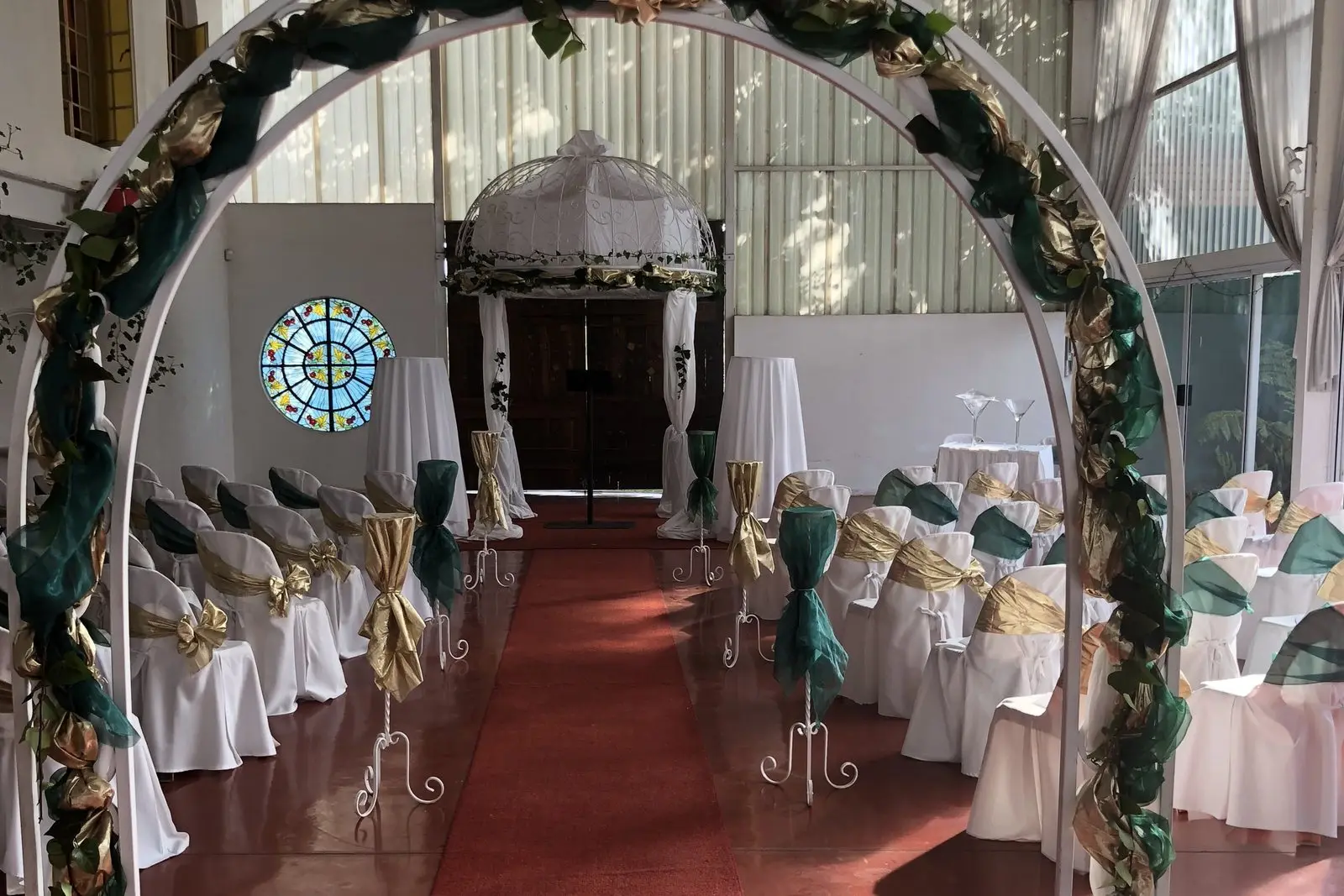 A floral arch set up inside the hall over a red carpet aisle