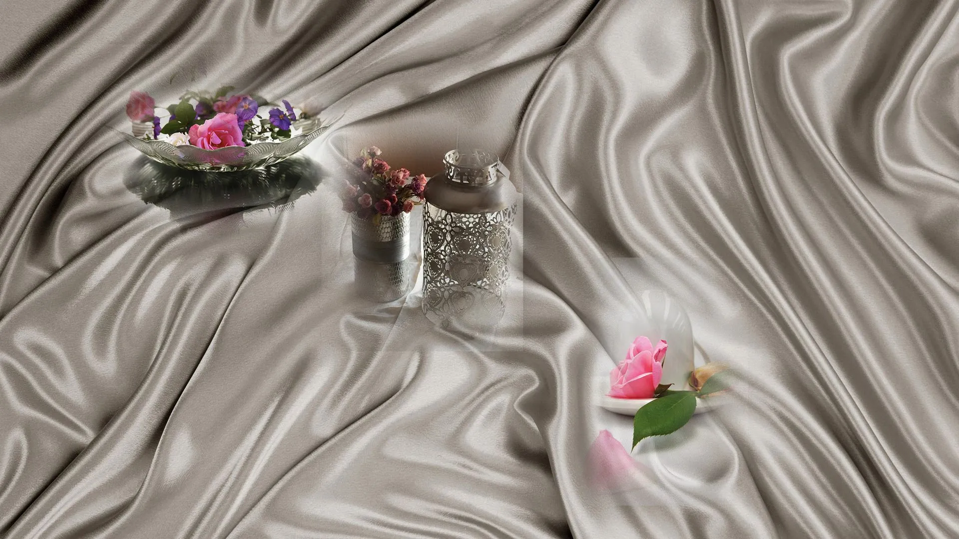 Decorative flowers and a lantern arranged on draped satin fabric