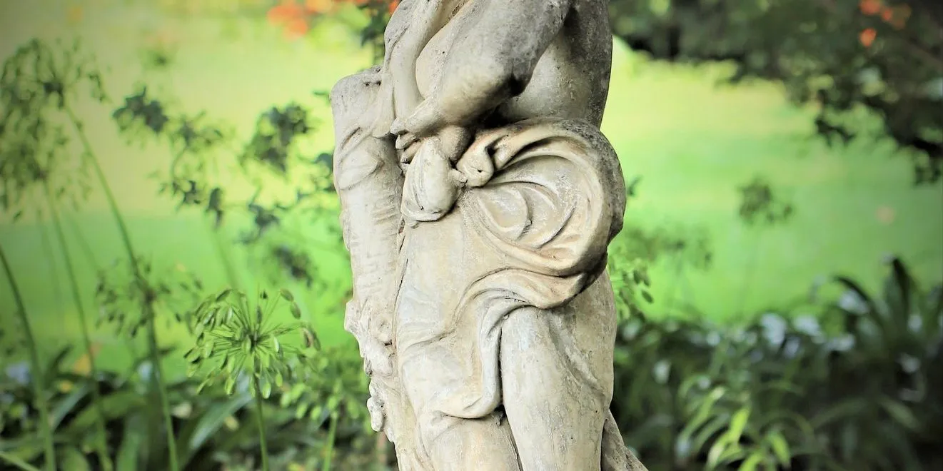 A stone garden statue among ferns on the property