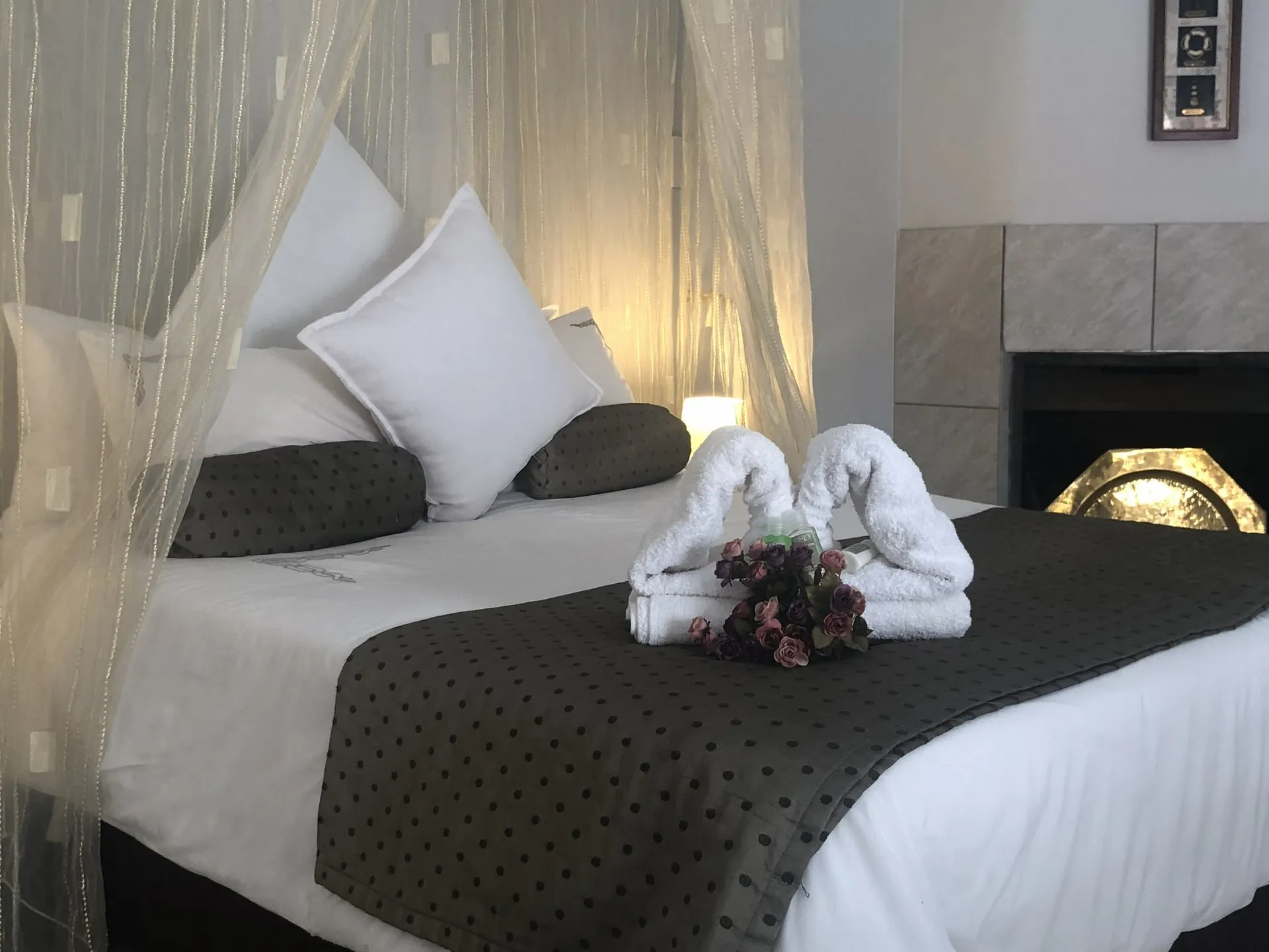 Towels folded into a swan shape on a canopied bed, with a small bunch of flowers