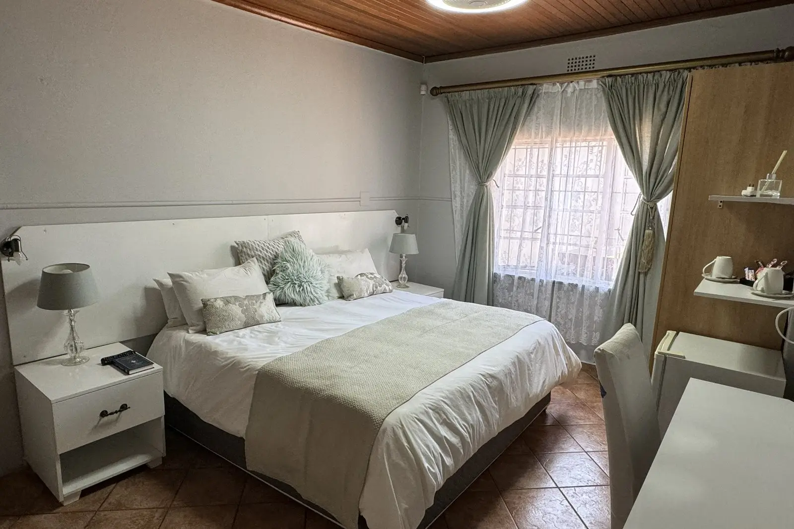 A spacious comfort room with a wood ceiling and view through to the en-suite