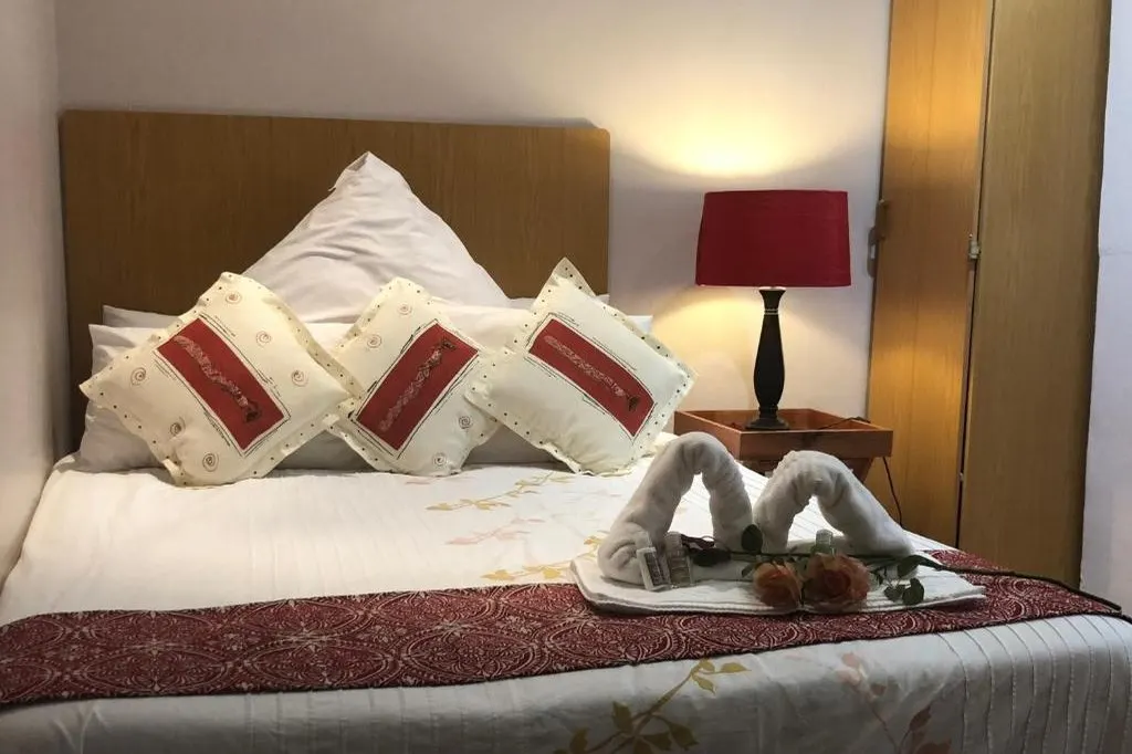 A double room with a bath, dark wood headboard and reading lamps