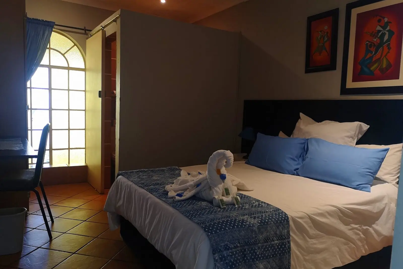 A room made up as a king bed with blue linen and natural light
