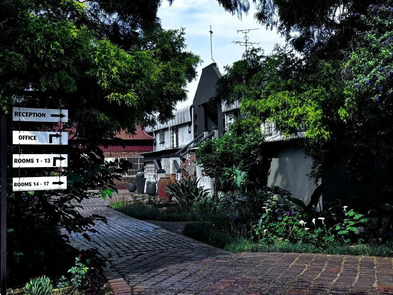 The brick garden path leading past directional signs to reception and the rooms