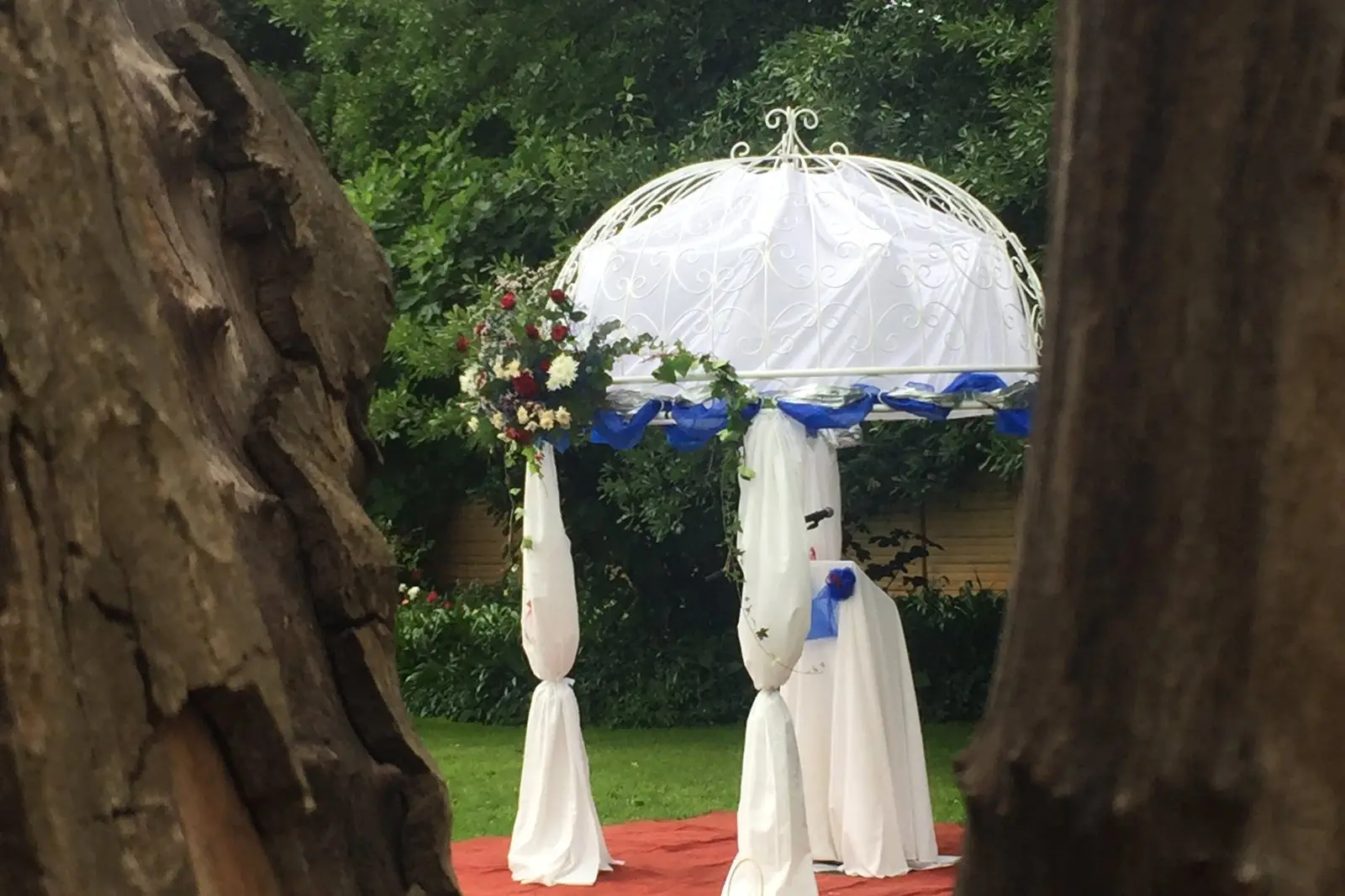 A draped white gazebo set up under the trees for a ceremony