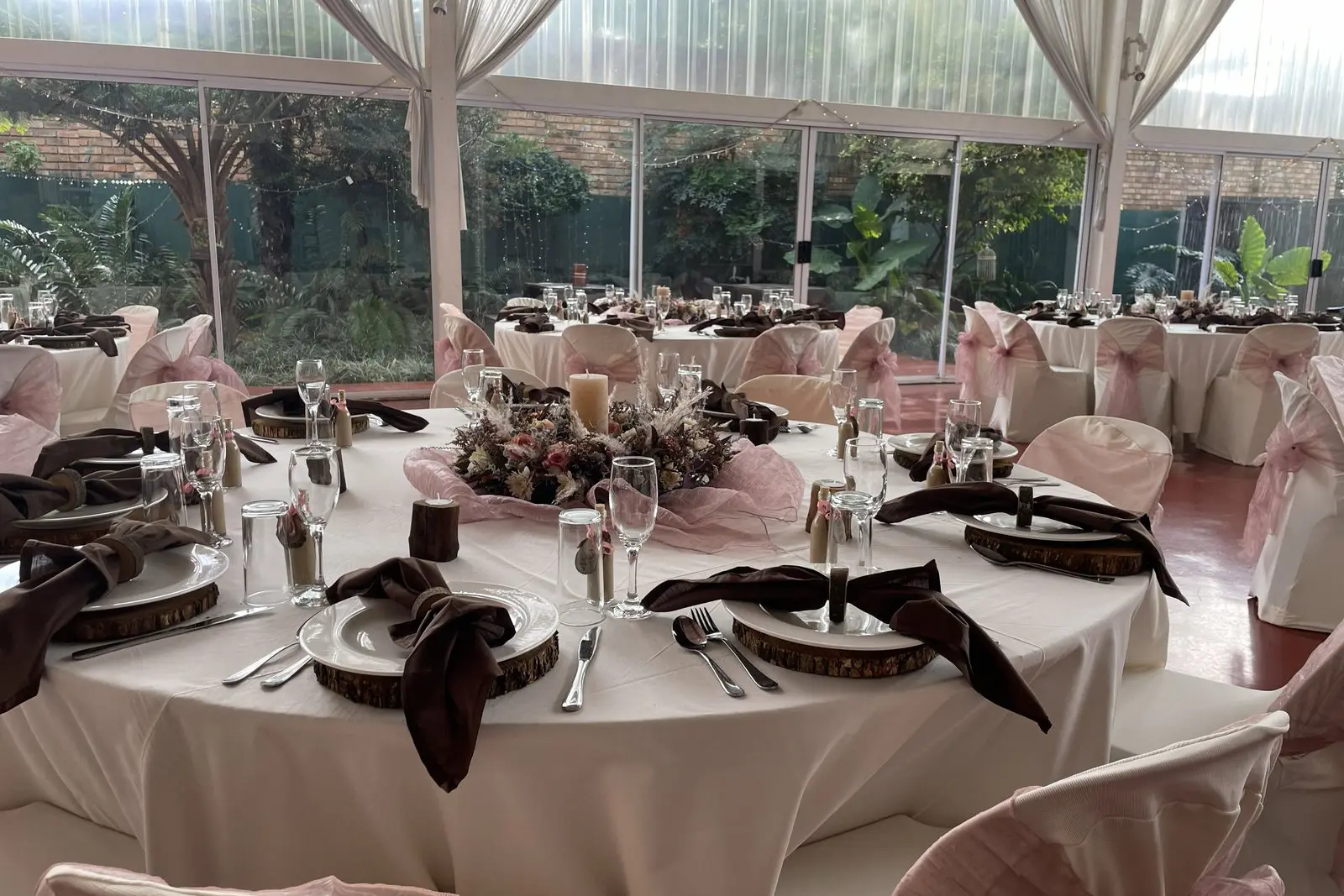 Round tables dressed in white and blush linen with roses for a function